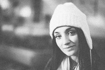 A young woman smiling in a white beanie