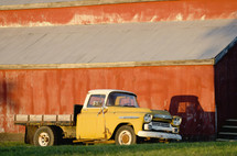 old flatbed truck parked in front of a red barn