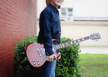a young man holding an electric guitar 