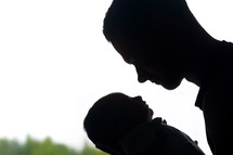 silhouette of a father holding a swaddled newborn 