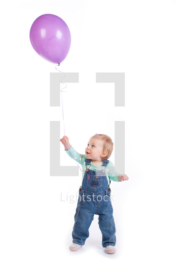 toddler girl holding a purple balloon 