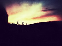 silhouette of a family walking away from a house at sunset 