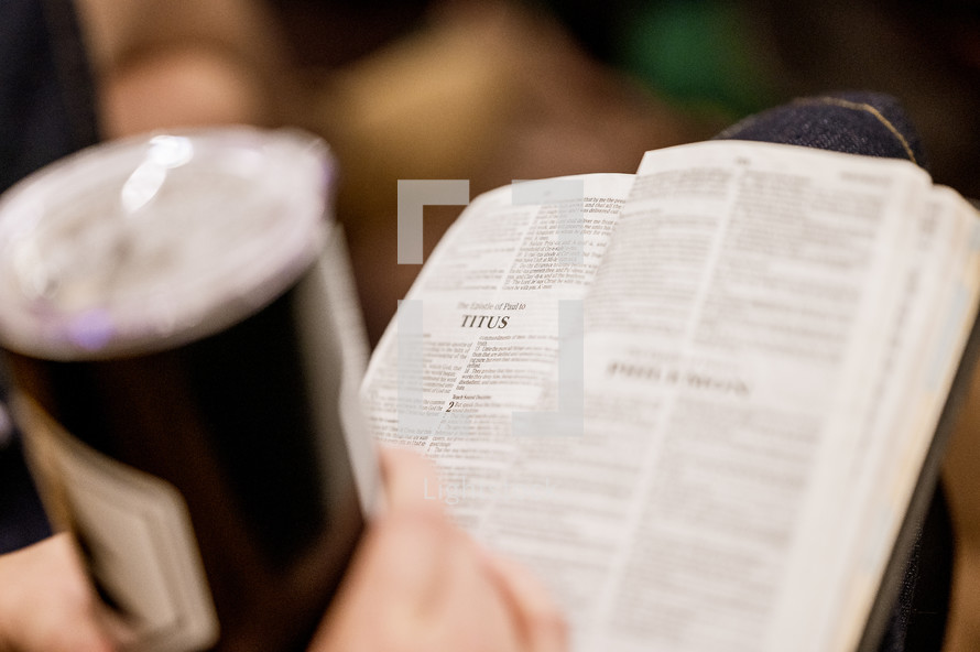 a person with a coffee cup and Bible in their lap