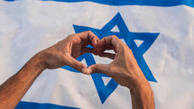 Hand in heart shape on Israel flag