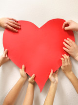 kids hands holding up a red heart 