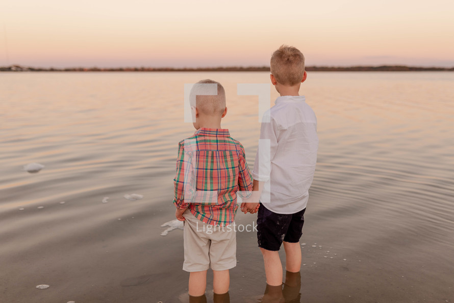 brothers holding hands standing on a beach 