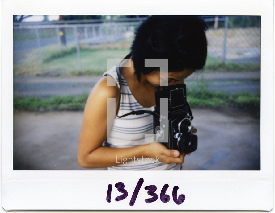 polaroid picture of a woman looking into a vintage camera 