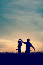 silhouettes of a couple dancing at sunset 
