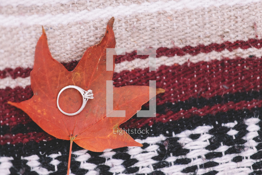 engagement ring on a fall leaf on a blanket 