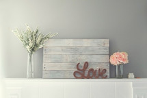 word love on a mantle and flowers in vases 