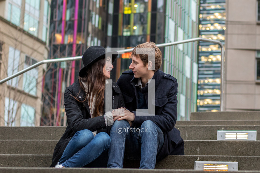 a couple sitting on concrete steps downtown 
