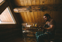 a man playing a guitar in a log cabin 