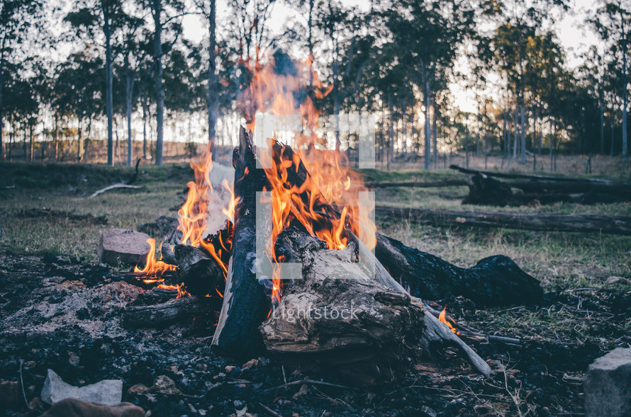 a campfire burns at dusk