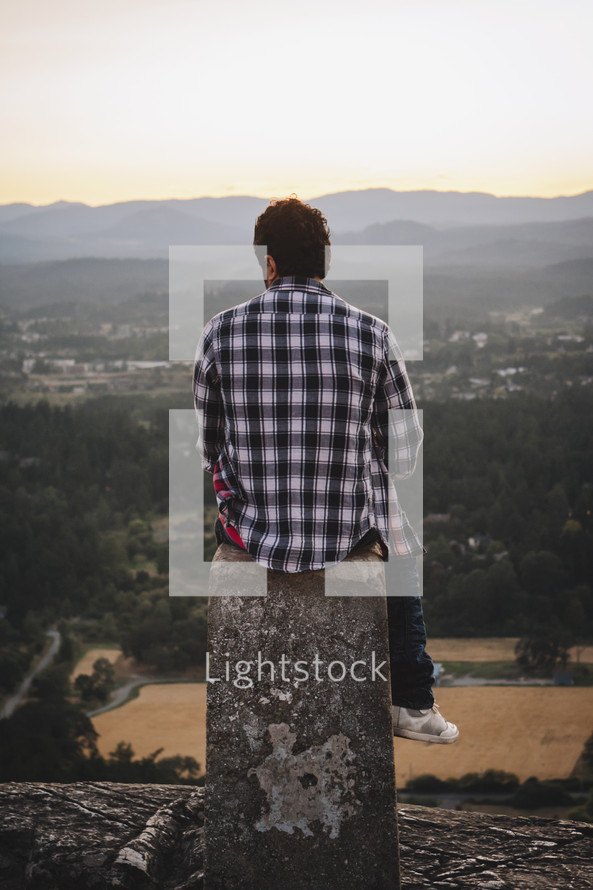 a young man sitting high on a hill