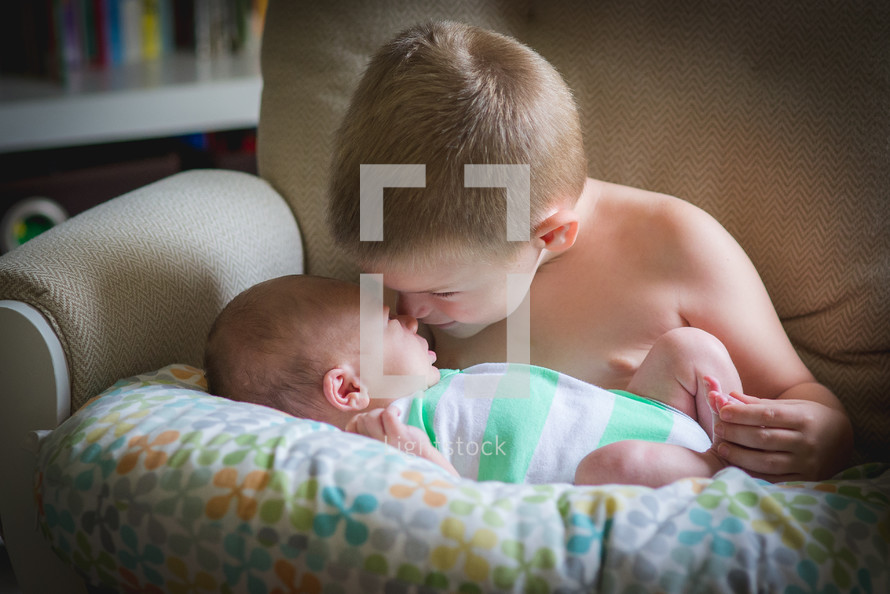a boy kissing his baby brother 