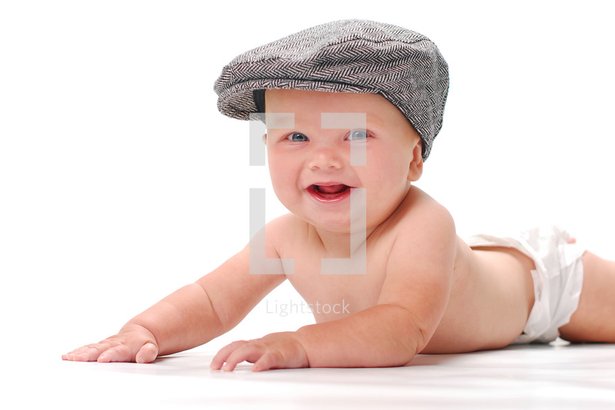 Infant boy laying on tummy in diaper and hat.