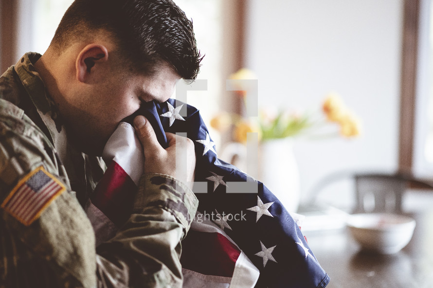 soldier crying into an American flag 