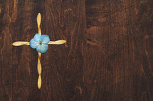 cross of flower petals on wood 