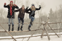 teen girls jumping off a fence in snow 