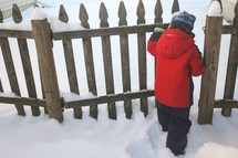 child opening a gate in winter snow 