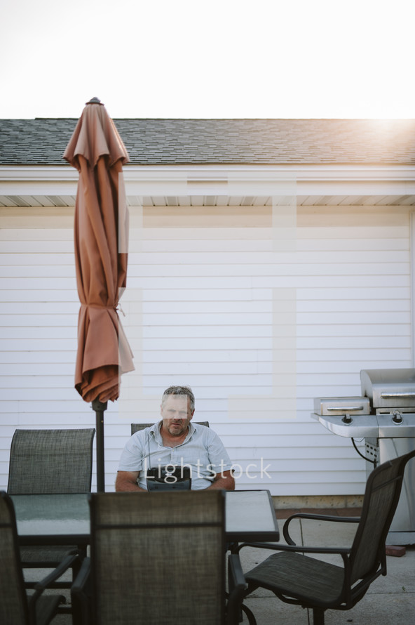 a man sitting at a table on a patio 