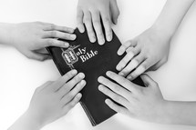 Children's hands on a closed Bible.