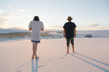 men standing barefoot on sand dunes 