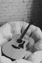 acoustic guitar resting in a bucket chair 