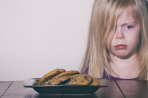 child frowning staring at cookies 