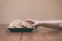child's hand grabbing a cookie