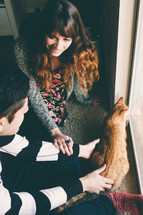a couple petting a cat 