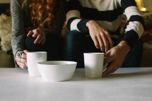 couple with coffee mugs on a coffee table 