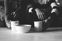 a couple with coffee mugs on a table 
