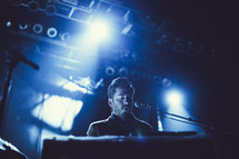 a man playing a keyboard and singing into a microphone at a concert 