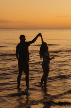a couple dancing in shallow water at sunset 