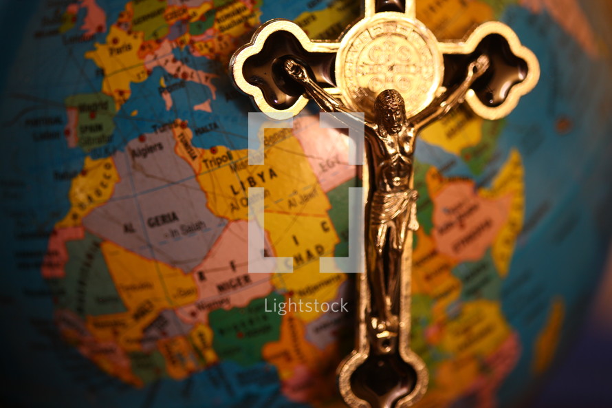 silver crucifix necklace on a globe