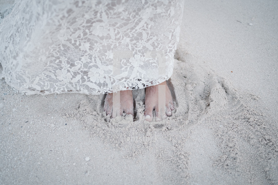 bride standing barefoot in the sand 