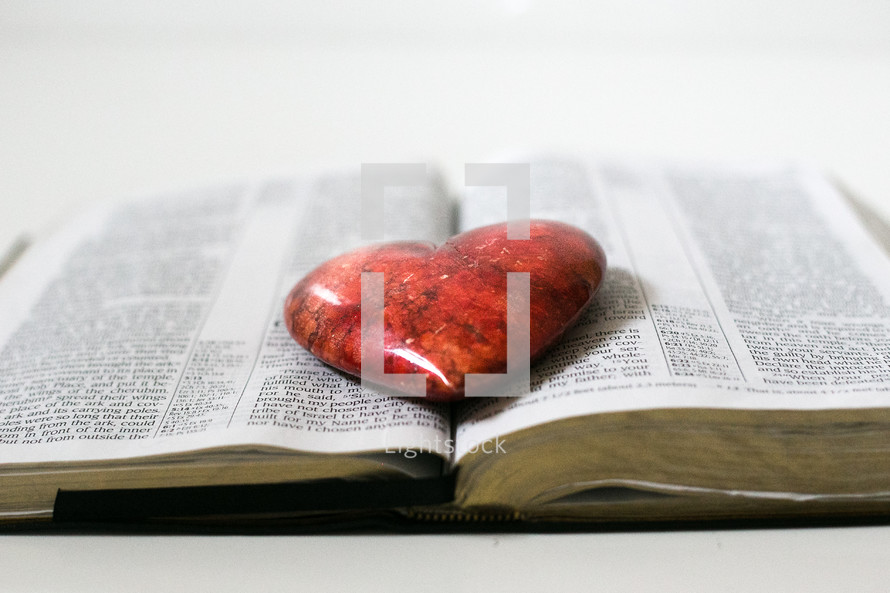 red heart shaped stone on the pages of a Bible 