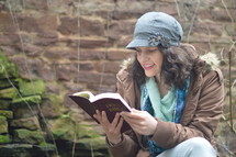 woman reading the bible while sitting outside.
