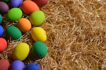 Colorful Easter eggs on a bed of straw.