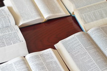 Bibles in different languages lying open on a table. 
