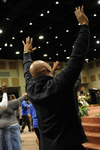 men and women with their hands raised praising God at a worship service 