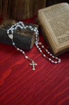 rosary on a very old ancient book in old German lettering on red wooden table