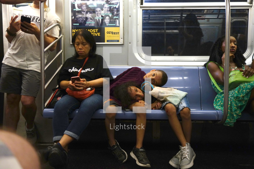 children sleeping on a subway train 