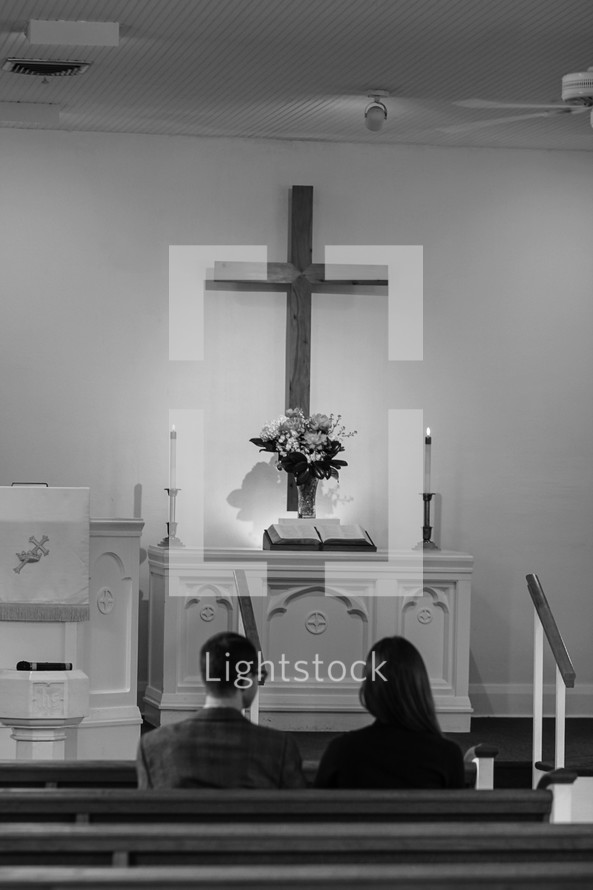 couple sitting in a pew looking up at the altar 