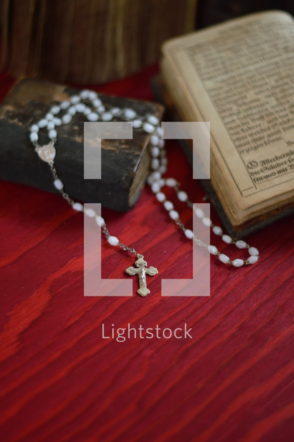 rosary on a very old ancient book in old German lettering on red wooden table