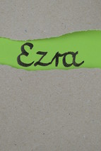 torn open kraft paper over green paper with the name of the book Ezra