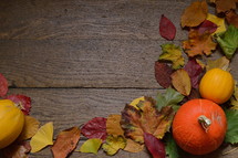 colorful autumn leaves and pumpkins on old wooden floorboards