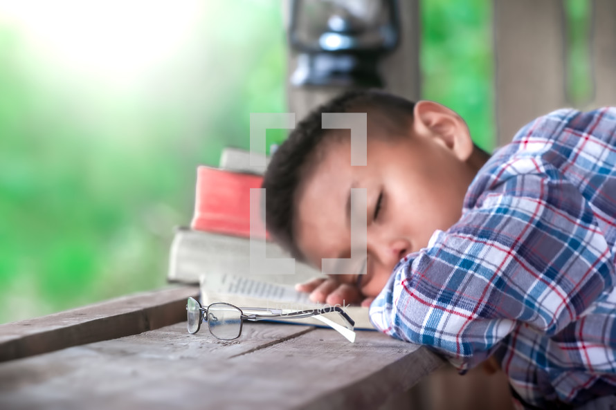 a boy sleeping on an open Bible outdoors 