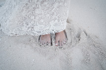 bride standing barefoot in the sand 